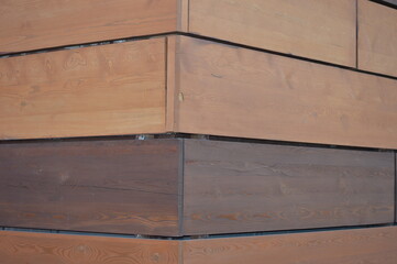 Building facade wall. Corner of the house. Finishing with decorative wooden light and dark panels. Beautiful brown wooden background.