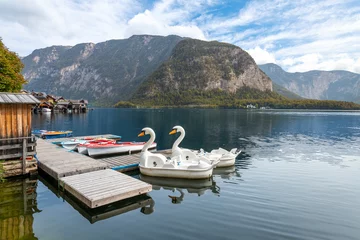 Deurstickers Two swan pedal boats wait for tourists at a small dock on the lake at Hallstatt, Austria. © Kirk Fisher