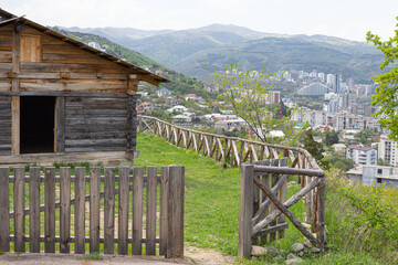 Fototapeta premium A traditional Georgian wooden farm building in Tbilisi Open Air Museum of Ethnography against the background of modern quarters of the capital. Georgia country