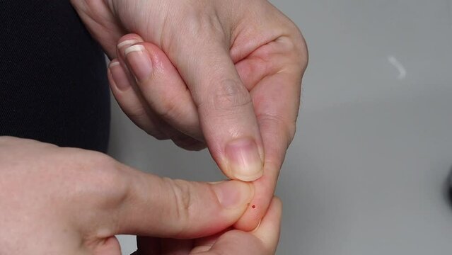 Woman's hands pricking her finger to measure her blood sugar in a glucometer