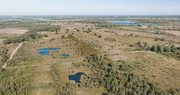 Aerial view of beat bog with lakes and people walking on wooden walking platform and walking paths in national park De Groote Peel, Limburg, Netherlands