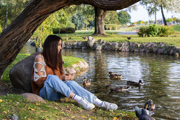 A girl feeds ducks on the shore of a pond