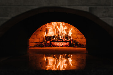 Firewood burning in the oven. Wood-fired oven. Image of a brick pizza oven with fire. A traditional...