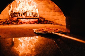 The chef puts the Margherita, four cheese or meat pizza on a shovel in the oven. A firewood oven...