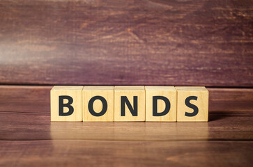 Concept of bonds. Word bonds on wooden blocks and wooden background