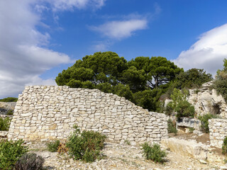 Fototapeta premium A white stone wall in Provence with Mediterranean pines in the background.