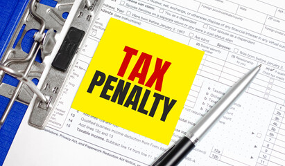tax penalty word on yellow sticker with tax form and pen