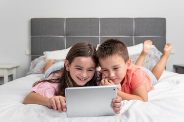 Cute little children with digital tablet using internet at home. Caucasian little sister and...