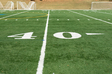 Obraz premium Green synthetic turf field at the 40 yard line on a clear autumn day with a shallow depth of field and copy space