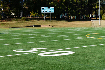 Obraz premium Green synthetic turf field at the 50 yard ine on a clear autumn day with a shallow depth of field and copy space