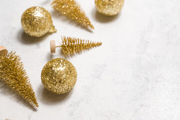 Christmas or new year flatlay with golden shiny ornaments on white concrete layed diagonally. Minimalistic background. Winter holidays concept