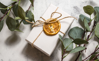 Minimalistic winter banner with gift box decorated with dry orange and brances of eucalyptus. Christmas,new year.