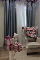 Decorated room with Christmas decorations, gifts, a snowman and a chair with a blanket.