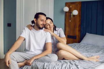 Fototapeta premium couple in love in white clothes is sitting on the bed in the bedroom in the morning.