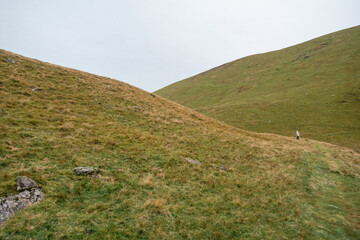 Person walking or hiking in raincoat near to Bowscale Tarn lake in mountains, United Kingdom