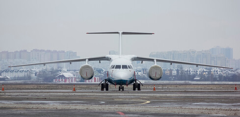 Jet passenger plane parked at the airport in the parking lot with engine covers on in winter against a cloudy sky