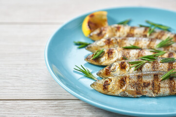 Baked fish with rosemary and lemon on a blue dish, copy space for text.
