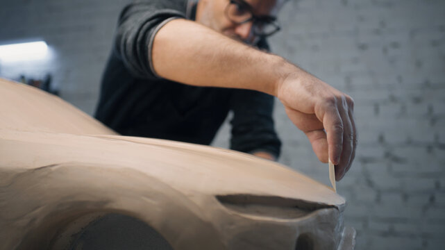 Car designer works closely on the sculpture of a prototype car using wire tipped tool to carve the car design. Makes design changes and perfecting it. Prototype model of the car.
