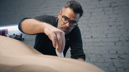 Car designer works closely on the sculpture of a prototype car using wire tipped tool to carve the car design. Makes design changes and perfecting it. Prototype model of the car.