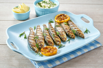 Healthy mediterranean cuisine of fried sardines and creamy sauce in a blue dish on a white wooden...