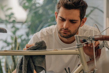 young man at home fixing and cleaning vintage bike