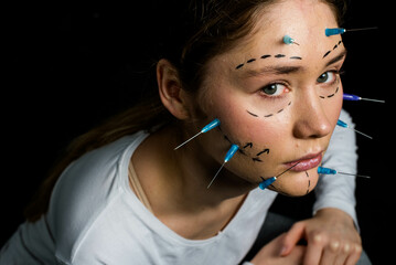 young beautiful girl with deep eyes looking into the camera. needles from syringes and arrows are...