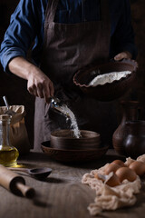 Man pouring flour for bread cooking and bakery ingredients for homemade cooking on table