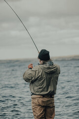 Fisherman immersed in the water of a lake with a fly rod