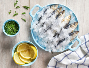fresh sardines with lemon, salt and rosemary close-up on a white table. Top view.
