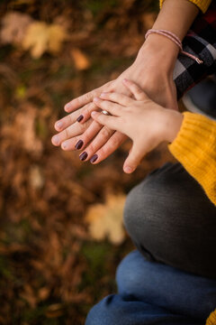 family photo: hands of dad, mom and little daughter. a walk in the autumn park. vertical photo, portrait
