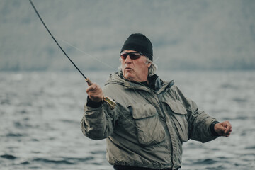Fisherman immersed in the water of a lake with a fly rod