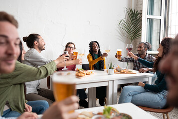 Multiracial group of friends having fun at pub drinking wine and  beer - Young people celebrating and laughing together at bar restaurant 
