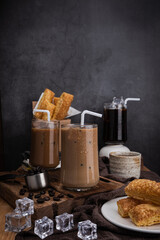 ice coffee in transparent glass and roasted coffee beans and Crispy Pie dessert on wood. black background studio. vertical photo