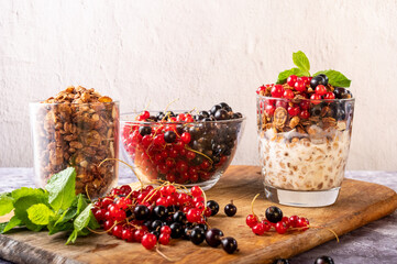 Berries and granola with yogurt. Red and black currants on the table. Berries in a glass bowl.
