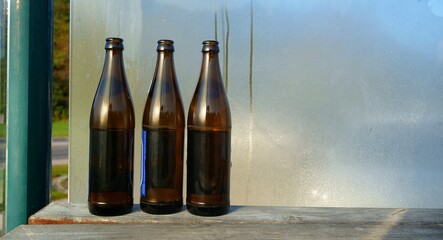 querformat, drei leere bierflaschen auf einer bank, jugendliche, party im öffentlichen raum,...