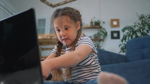Happy toddler girl playing video games at home. Child controls game controller. girl gamer with help of control panel plays a computer game. Video game console for playing at home
