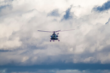 Fototapeta na wymiar A military helicopter flies against the background of an overcast sky and against the background of heapy clouds, front view 