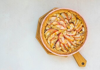 Dessert, round apple pie or shortcrust pastry tart with apple slices and almond petals in a pink...