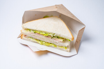 sandwich with ham cheese and herbs in a craft cardboard box