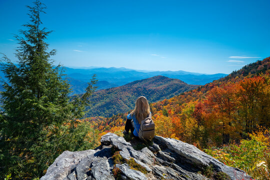 Woman Relaxing On Fall Hiking Trip. Girl Sitting On The Rock On Top Of The Mountain Enjoying Beautiful Autumn Scenery. Blue Ridge Mountains, Near Asheville, North Carolina, USA