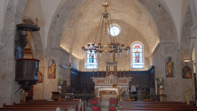 View inside of a church. Action. Empty rows of sits, chandelier with candles and stained glass windows.