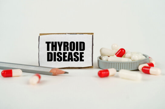 On a white background, medical capsules, a pencil and a cardboard plate with the inscription - Thyroid disease