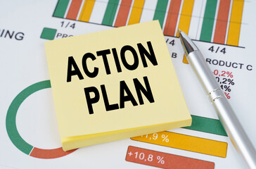 On the business charts are a pen and stickers with the inscription - ACTION PLAN