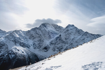 View of the mountain range, steep slopes and snow-capped rocky peaks. Selective focus.