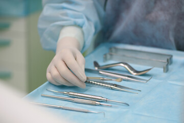 Surgical instruments in the operating room. A surgeon preparing for a tooth implantation and sinus lifting operation
Dental probe, curettes tweezers, scalpel, needle holder, rasps on instrument table.