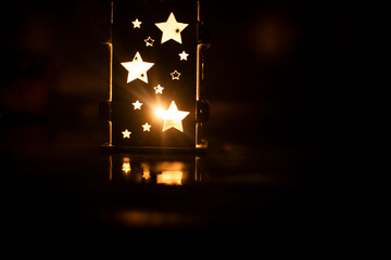 burning candle in a ceramic lamp with stars in the dark in the room. Christmas evening.