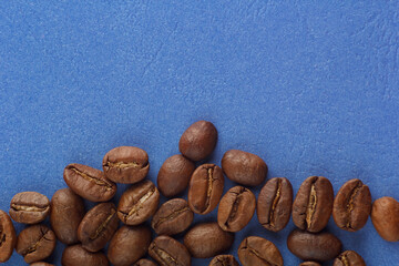 coffee beans are scattered on a blue background from the edge of the frame. Coffee on a blue background