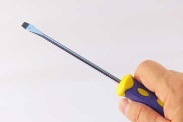 The hand holds a screwdriver with an insulated handle on a white background.