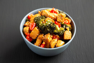 Homemade One-Pan Chicken And Broccoli Stir-Fry in a Bowl on a black background, side view.