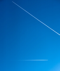 high altitude contrails (jet airplane vapour trails) across a deep blue clear sky